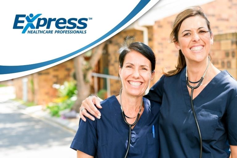Two happy female caregivers in dark blue scrubs